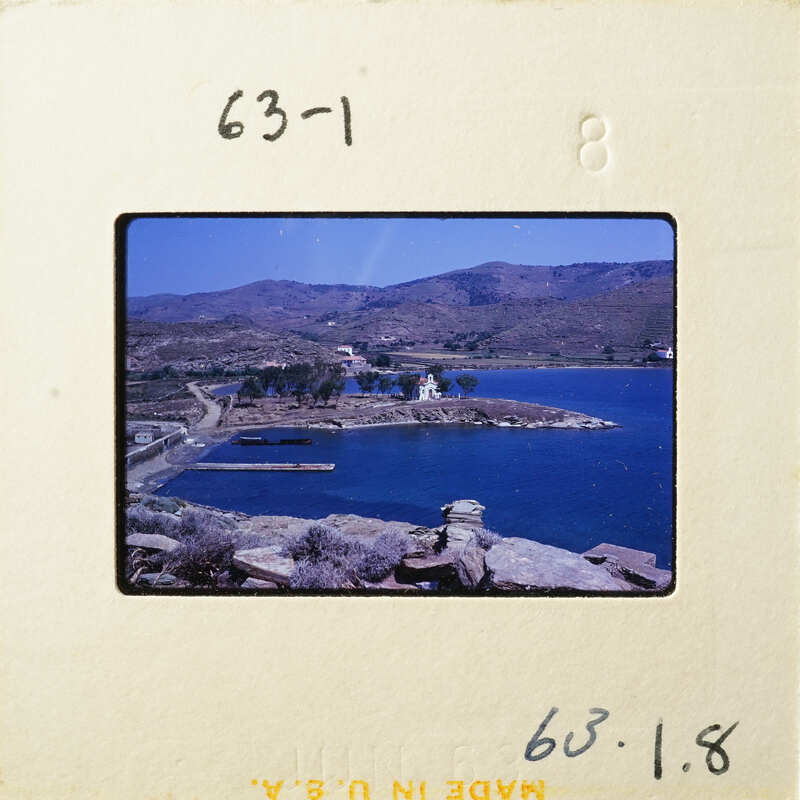 A photograph of a scenic coastal landscape with mountains, water, and greenery.