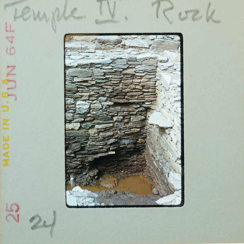 Interior corner of tall stone wall with floor under muddy water.
