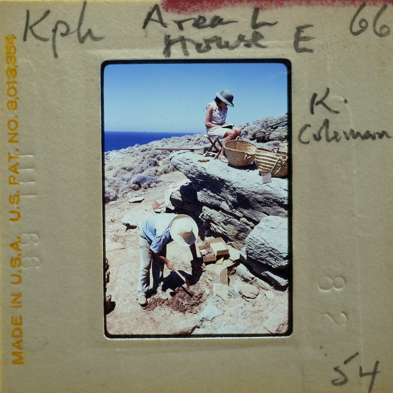 Two people working on a stone wall near the ocean with blue sky and clear weather.