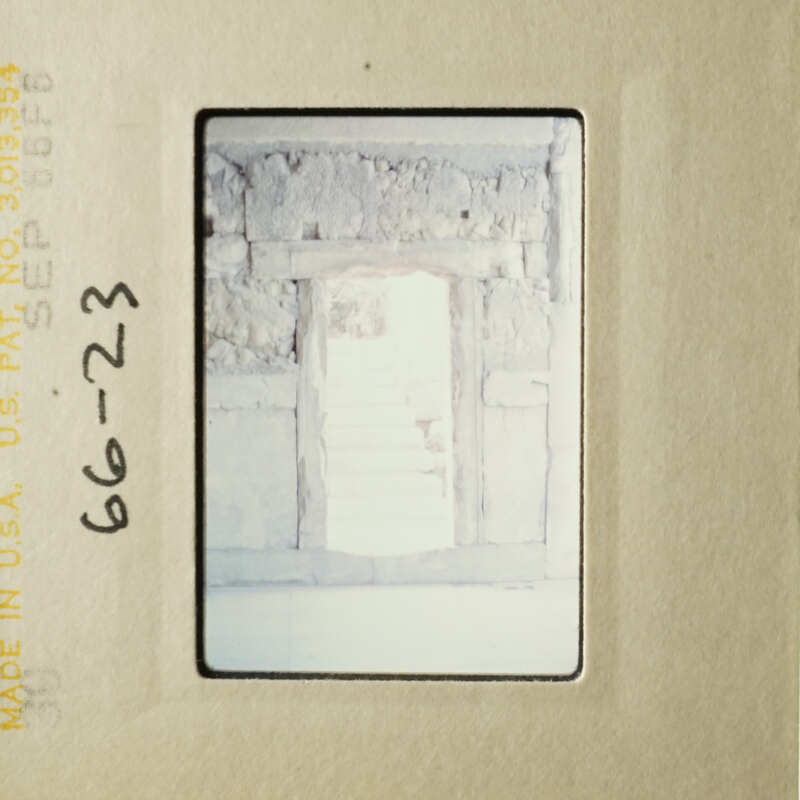 A photo of an old, dilapidated building with a doorway and steps.