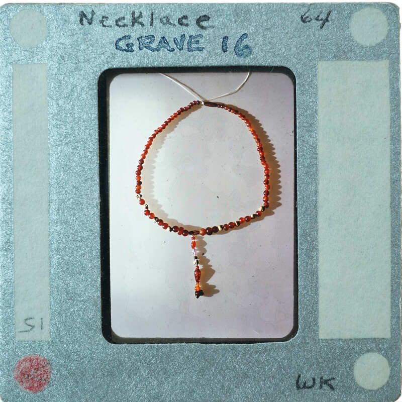 A bracelet with red and black beads on a display card.