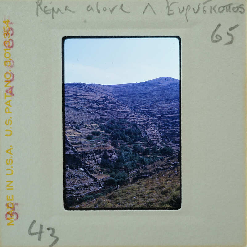 A photograph of a mountainous landscape with greenery, presented on a film strip.