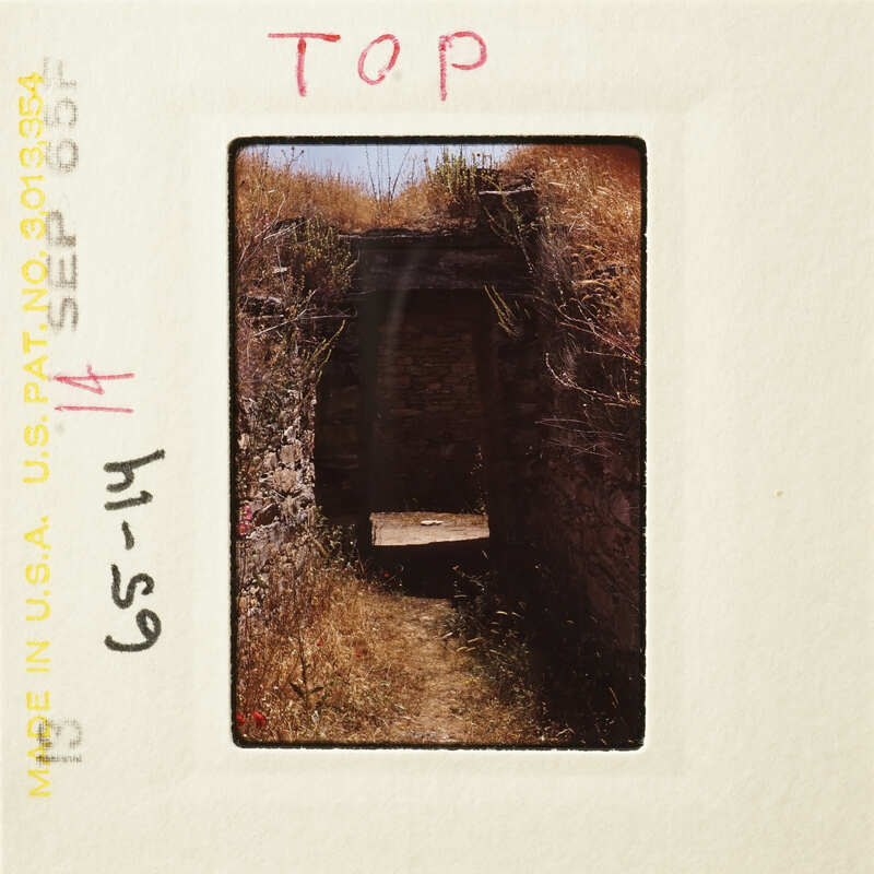 A photograph showing an old, weathered stone archway with overgrown vegetation.