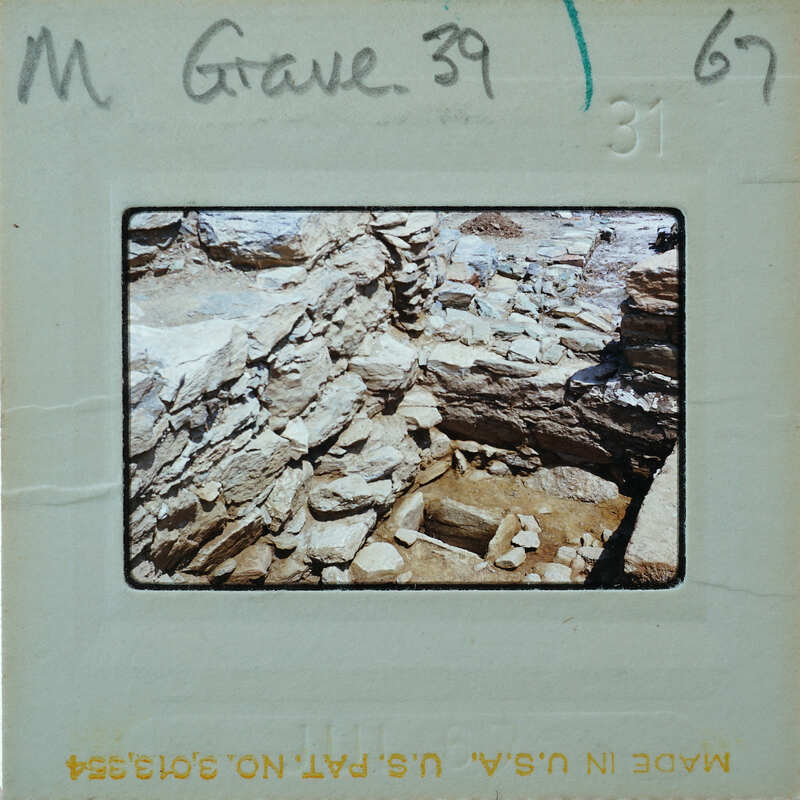 The image is a photograph of an archaeological site with stone ruins, possibly part of a historical excavation or investigation.