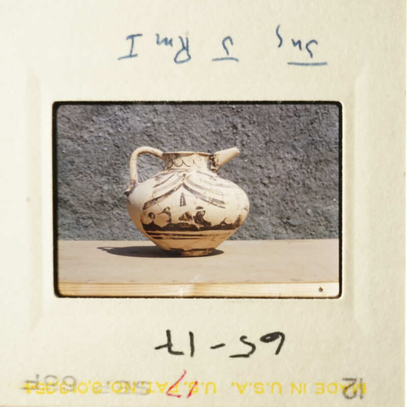 A vase on display, with a handwritten note and a timestamp stamp.