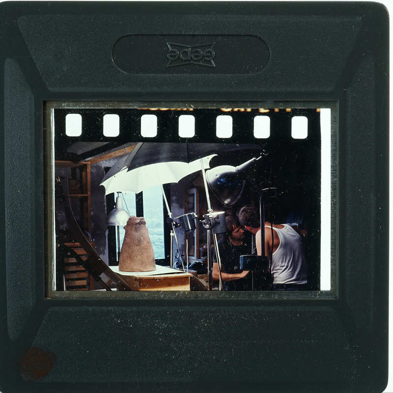 Terracotta figurine skirt being readied for photography with two people setting it up.