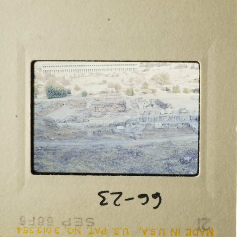 The photo shows an ancient Greek city with ruins and stone structures, captured through a vintage film strip.