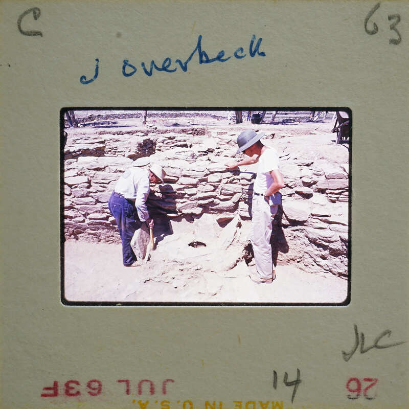 Two men working on a stone structure, possibly an archaeological site.