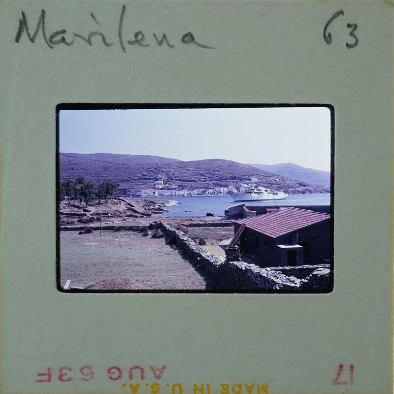 A vintage photograph of a coastal landscape with hills, water, and buildings.