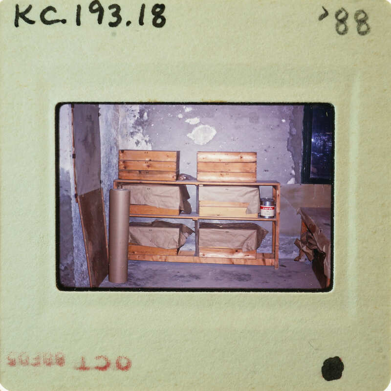 Photo of a room with wooden furniture and peeling paint on the walls, taken from an old slide.