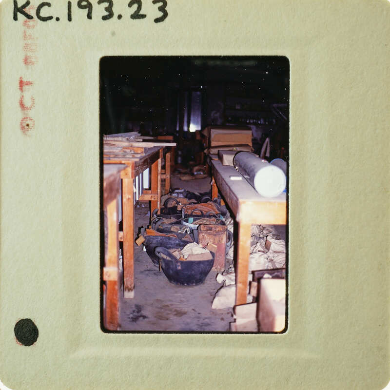 A vintage photograph of a cluttered workshop with wooden benches and various tools.