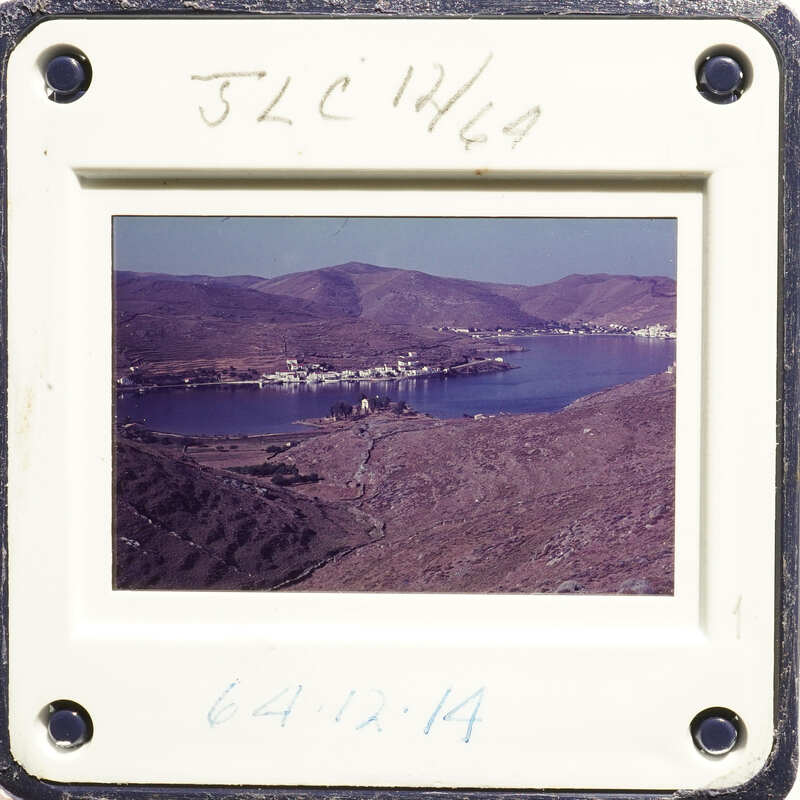 Mountains and water body with buildings on shore, framed by white border.
