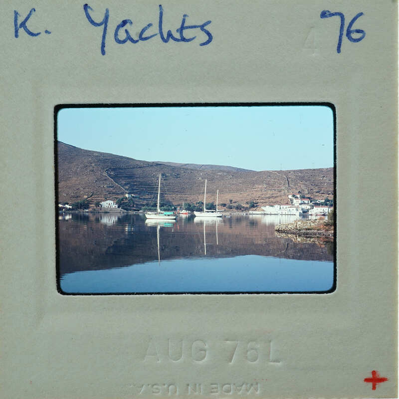 A vintage photo of a serene harbor with boats and mountains, dated August 1976.