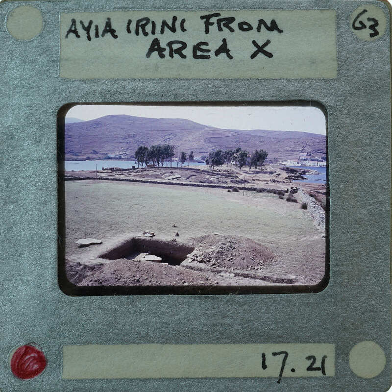 This is a vintage photo of an archaeological site with ruins and mountains in the background, presented on a film strip card labeled "AYA IRINI FROM AREA X".