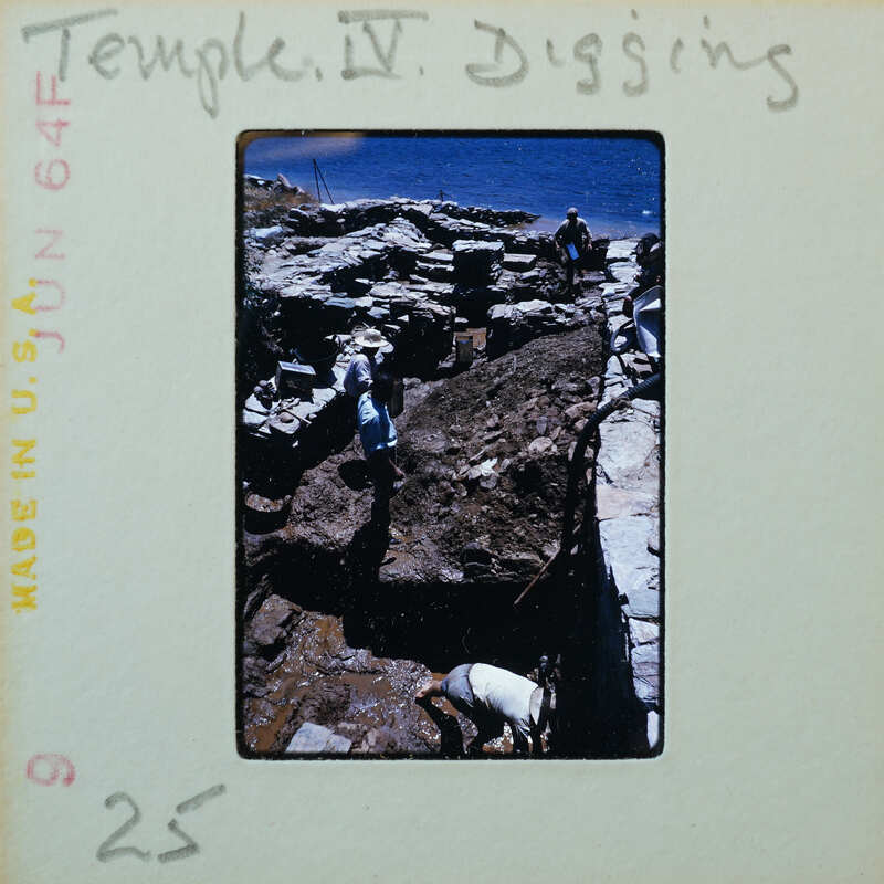 Three workers working on stone walls, partially under muddy water and the sea in the background.