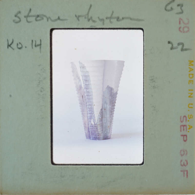 A photograph of a ceramic vase with an intricate design, displayed on a vintage postcard.