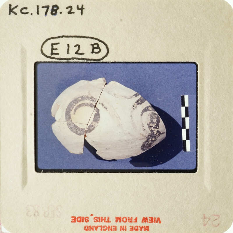 Old photograph of an artifact with markings, possibly a shell or pottery piece.