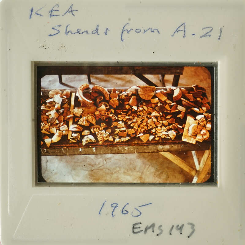 A photograph showing a table with various objects, possibly pottery shards, dated from 1986.