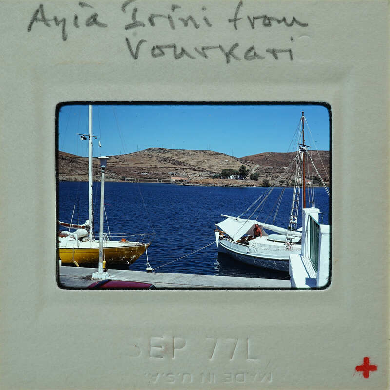 A vintage photo of a harbor with boats and hills in the background.