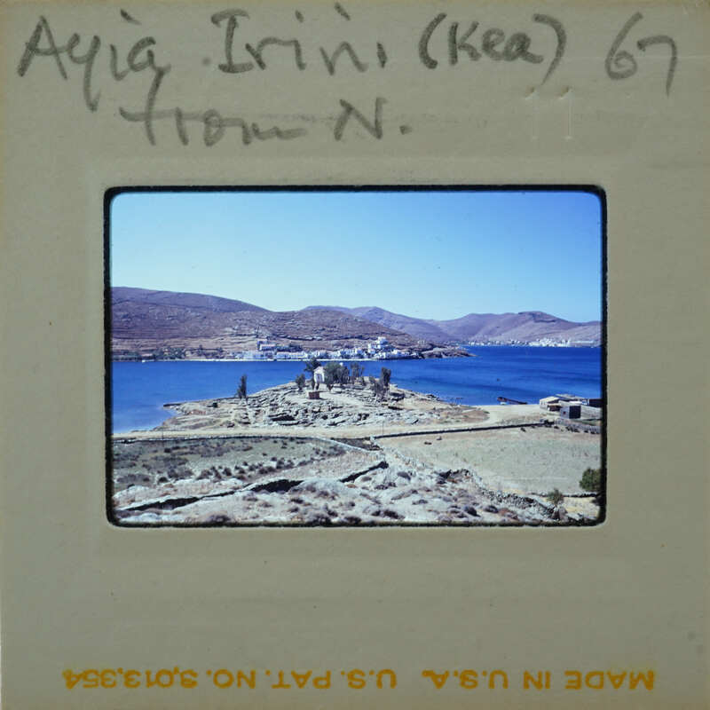 Photograph of a coastal landscape with mountains, water, and ruins.