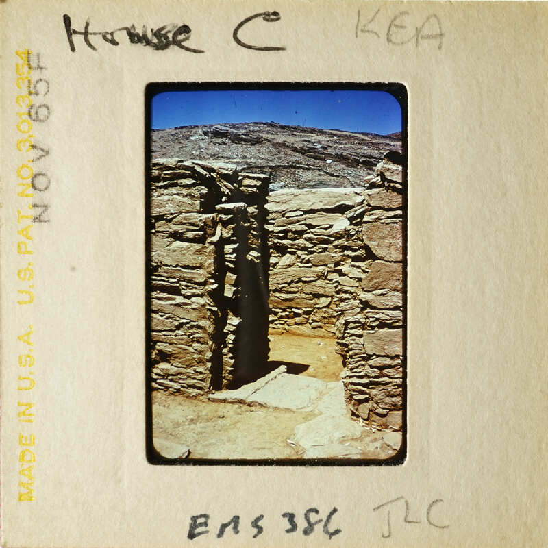 The image shows an ancient stone structure with a doorway, possibly ruins from an archaeological site.