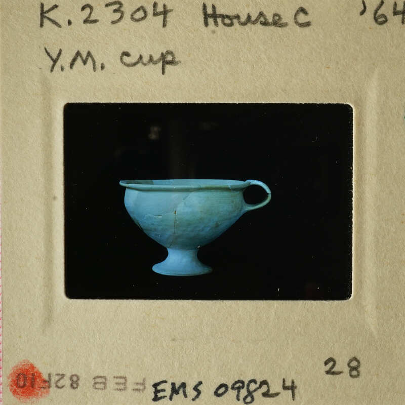 Blue ceramic cup with handle on black background.