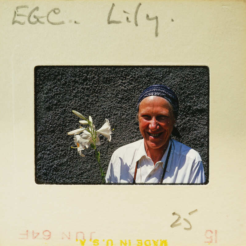 A woman holding a flower, smiling at the camera.