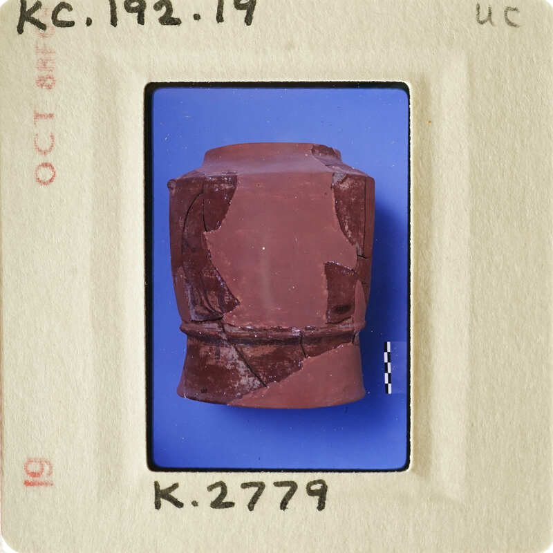 Ancient ceramic artifact with visible cracks and imperfections, displayed on blue background.