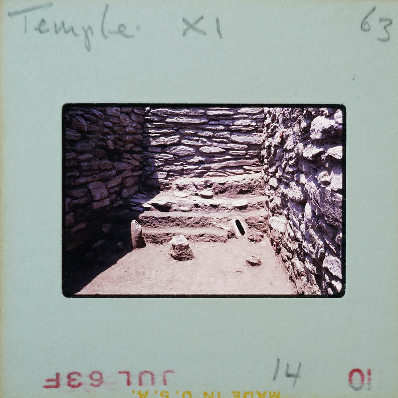 An old stone structure with a dirt floor and steps, possibly part of an ancient temple or ruins.