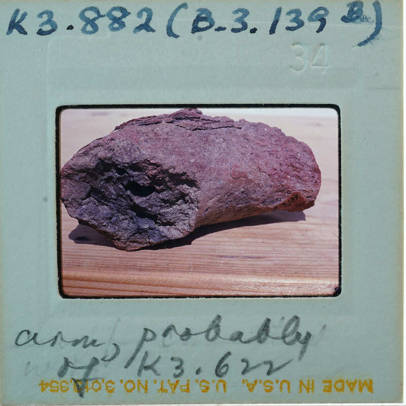 A close-up photograph of a rock with an old Polaroid border and handwritten notes on the back.
