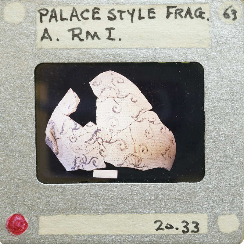 A photograph of an ancient Greek vase fragment with a visible handle and intricate patterns.