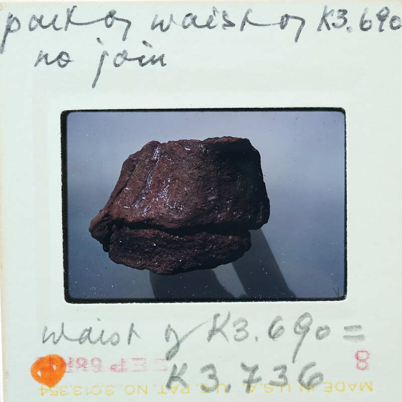 A close-up photo of a rock with handwritten notes on the back of the photo.