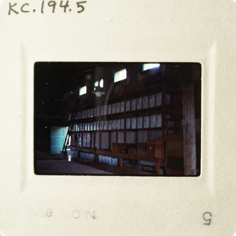 A photograph of an empty room with many shelves and boxes, taken from a low angle.