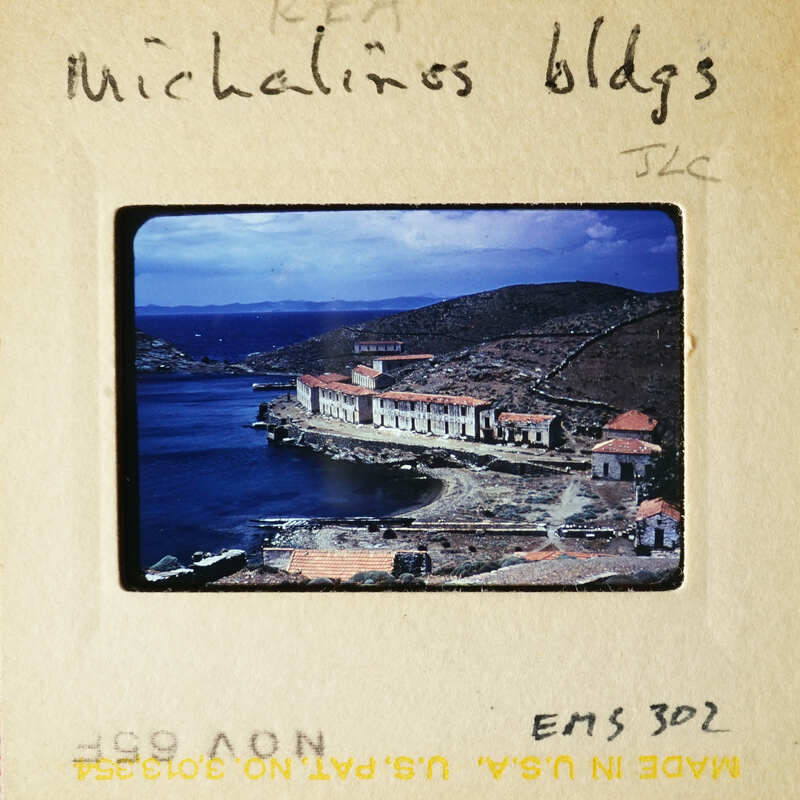 A photograph of an old slide showing a coastal village with buildings and water.