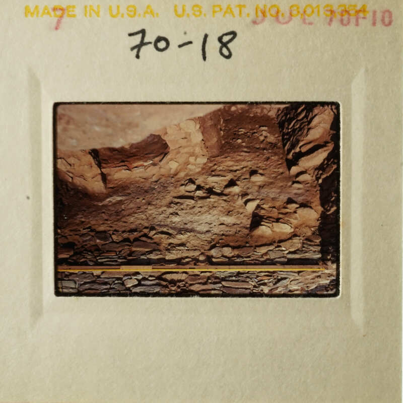 This is an old photograph depicting a rocky landscape with a small structure, possibly a cave entrance, and some debris on the ground.