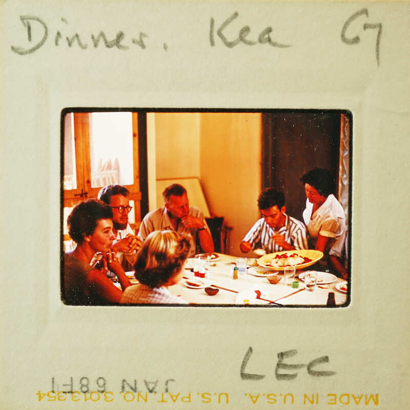 A vintage photo of a family gathered around a dinner table, with an old-fashioned appearance.