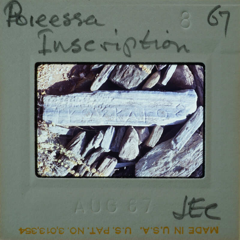 Old photo of a rock with writing on it, displayed on an aged piece of paper.