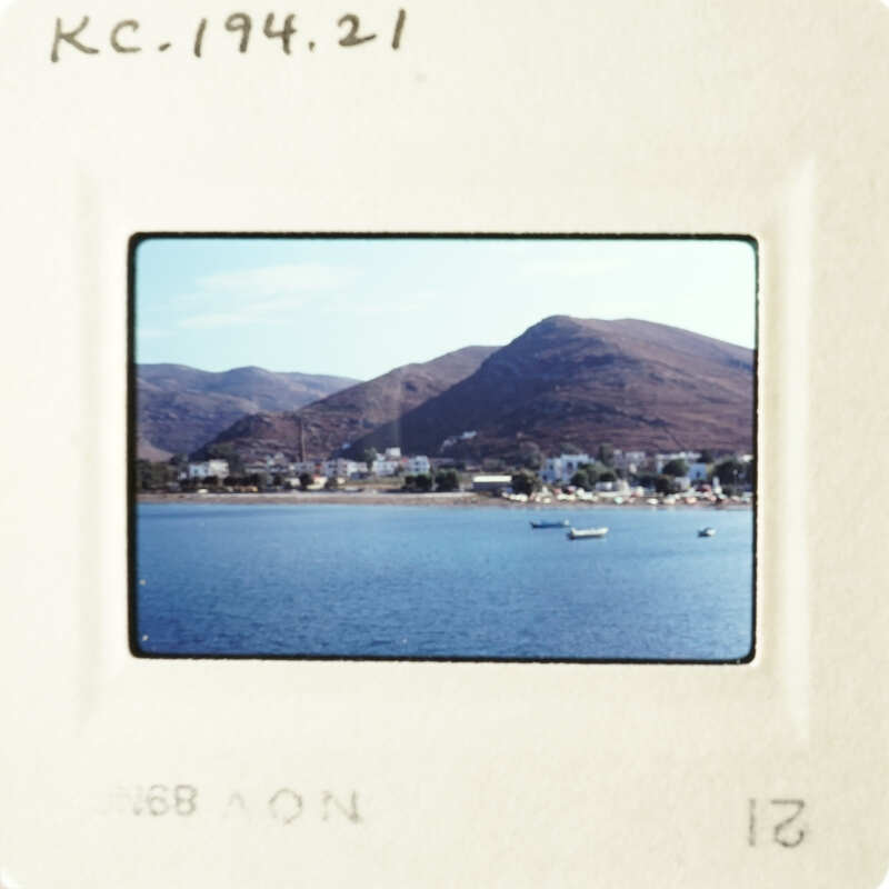 A tranquil coastal scene with boats on the water and mountains in the background.