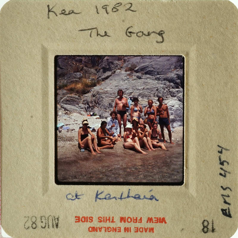 A group of people posing on a rocky beach, with a vintage look.