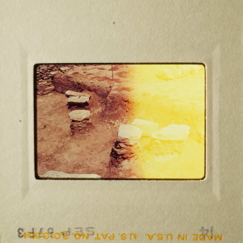 The photo shows an ancient archaeological site with stone ruins and a yellowish tint.