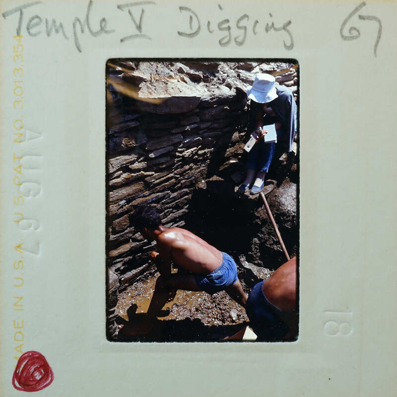 Two men excavating a muddy surface.