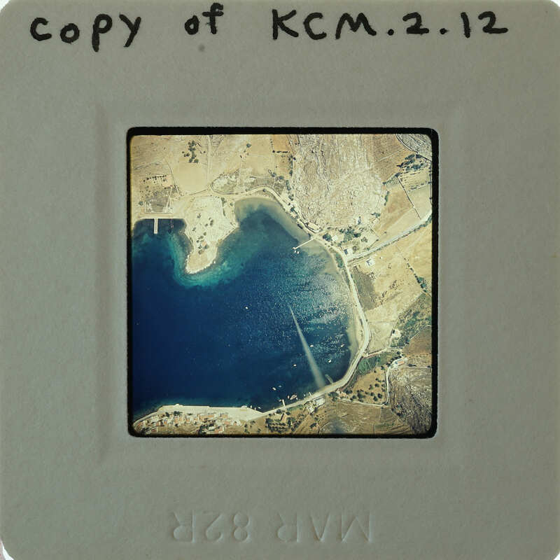 Aerial photograph of a coastal area with blue water and land features, on an old-fashioned film strip.