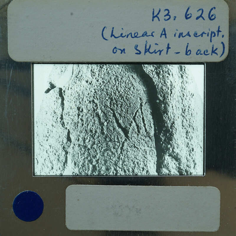 A black and white photograph of a stone surface with markings, displayed on an old-fashioned film strip.