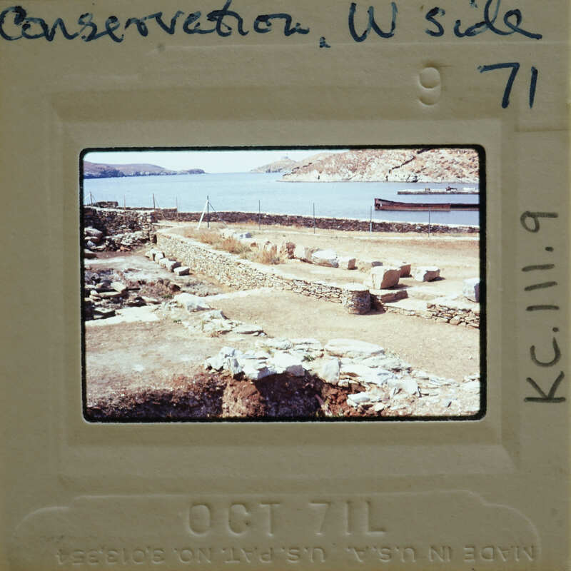 A vintage photo of an ancient stone structure near a body of water, with a date stamp on the bottom right corner.