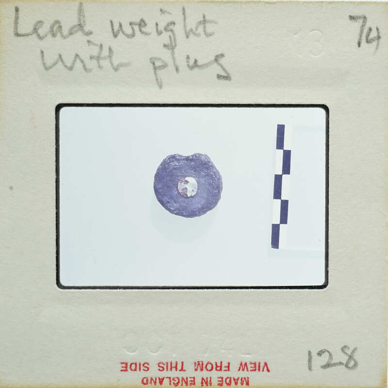 A small, purple gemstone with a white background and measurement lines on a card.