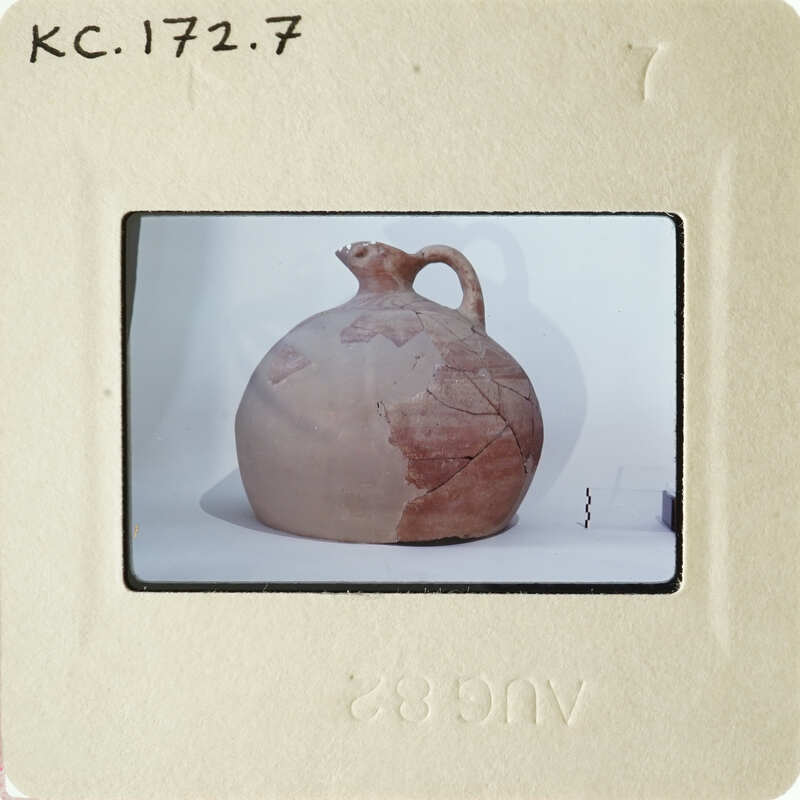 Ancient clay pot with visible cracks and chips, photographed on a white surface.
