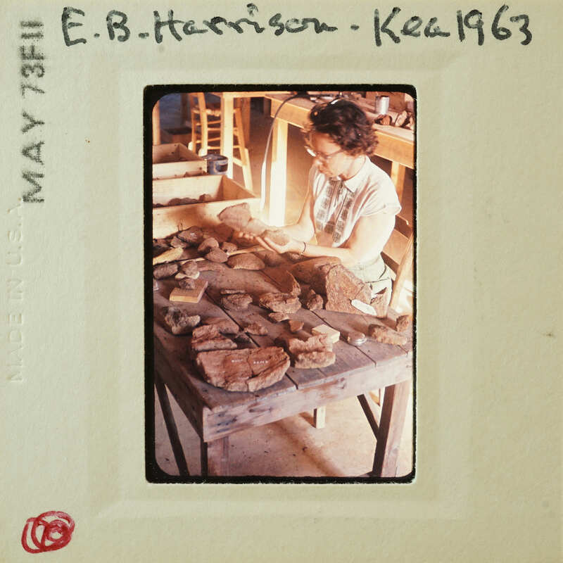 A vintage photo of a woman working on pottery with clay pieces in front of her.