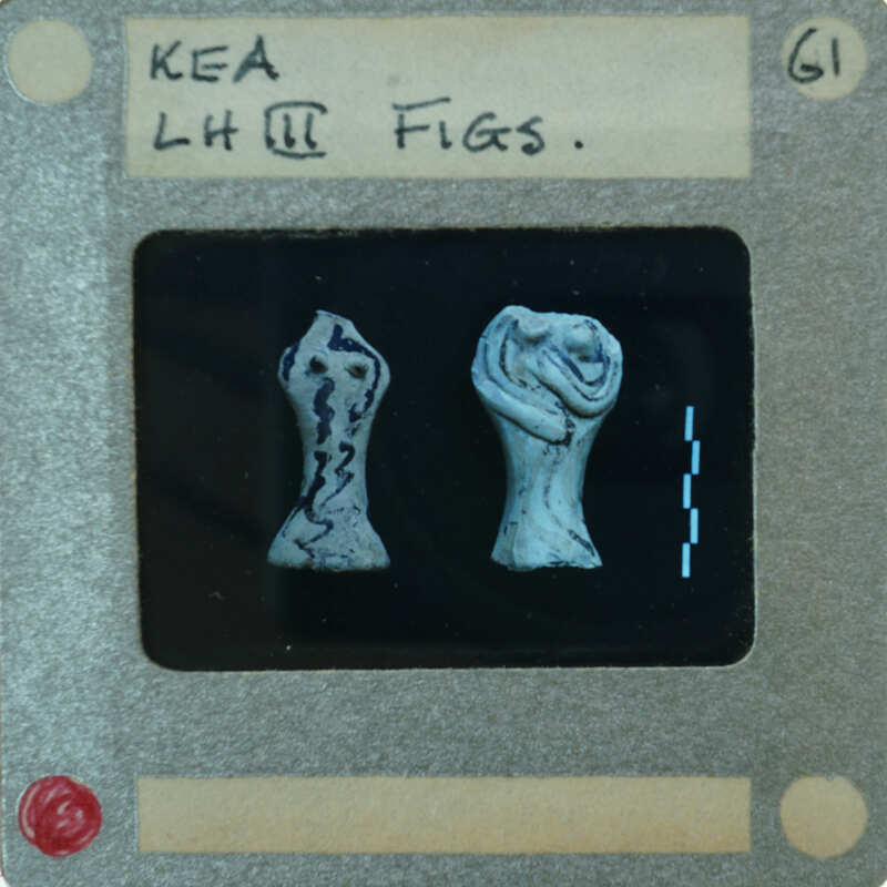 Two small figurines on a display card with labels and measurements.