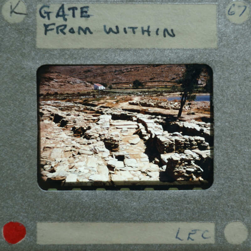 A photograph of an ancient stone structure on a film strip with the title "GATE FROM WITHIN" written above it.