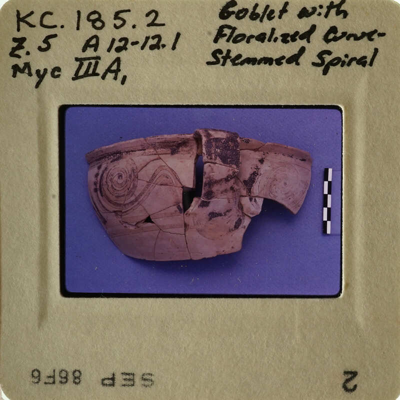 Ancient Greek vase with floral pattern and human face design.